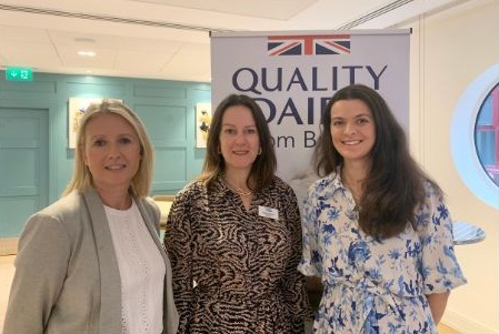 Three women standing in front of an AHDB Dairy sign.